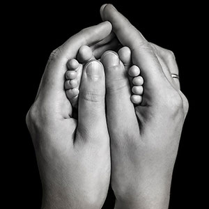 kleine zehen zwischen mamas händen in schwarz weiß. schwarz weiß fotos sehen sehr schön aus bei babyhänden und -füßen